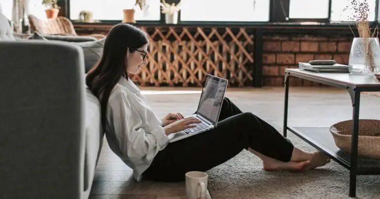 Woman with brown hair sitting on the floor with a computer in her lap