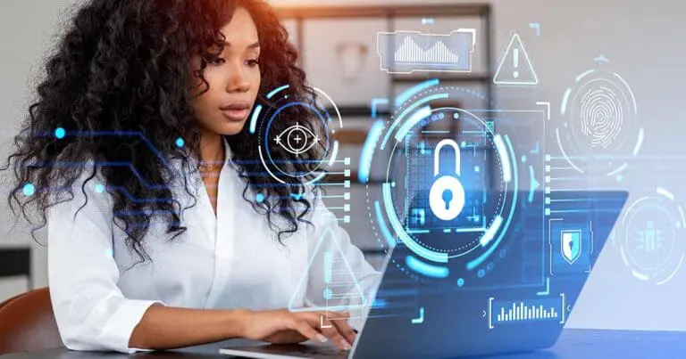 Image of a black woman with long curly hair in a white shirt sits at a computer with graphics of locks to signify cybersecurity