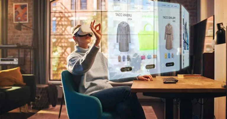 a woman wearing a VR headset sits in a blue chair with her arm up to select a floating image of a sweater in front of her to symbolize virtual reality shopping