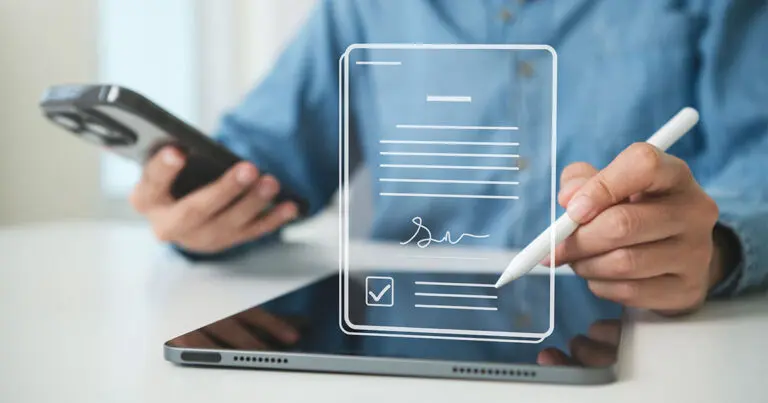 A person holds a smartphone while using a stylus on a tablet, with a digital illustration of a signed contract and checkmark overlaid on the screen. The imagery represents smart contracts and the automation of digital business agreements.