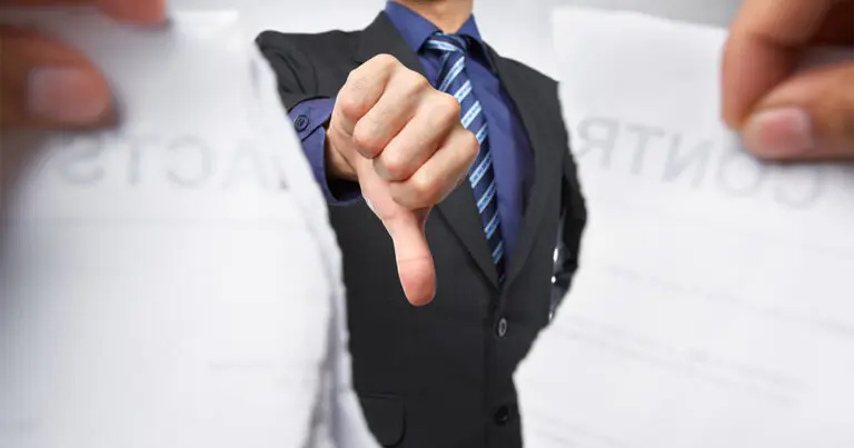 A person in a business suit gives a thumbs-down gesture through a torn contract, which is being ripped apart by two hands in the foreground. The image symbolizes job offer rejections, failed negotiations, or hiring missteps, illustrating the consequences of a breakdown in the recruitment or employment process.