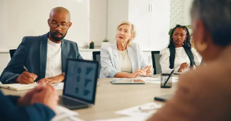Diverse leadership team in a boardroom having a strategic discussion, reflecting how to promote career building in your company through mentorship, cross-functional collaboration, and inclusive leadership development.