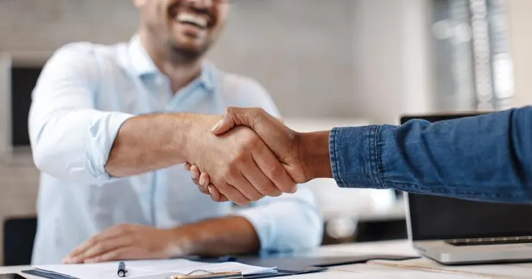 Two professionals shaking hands in a successful interview setting, highlighting how to promote the 3 C's in your company by fostering speed, clarity, confidence, commitment, and streamlined hiring practices.