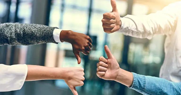 Group of diverse hands giving thumbs up and thumbs down, representing disagreement and alignment challenges in how to staff for AI when your exec team can’t agree on a strategy.