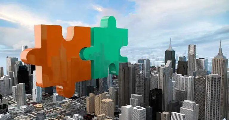 Two large, glossy puzzle pieces—one orange and one teal—float above a dense city skyline, aligned as though about to interlock. The skyscrapers below appear detailed and uniform, creating a contrast between the realistic urban setting and the oversized, stylized puzzle shapes.