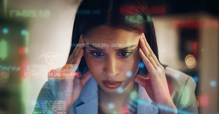 A woman with black hair looking stressed out with her hands at her temples as she looks a a computer screen and overlayed iages of charts and graphs and numbers float around.