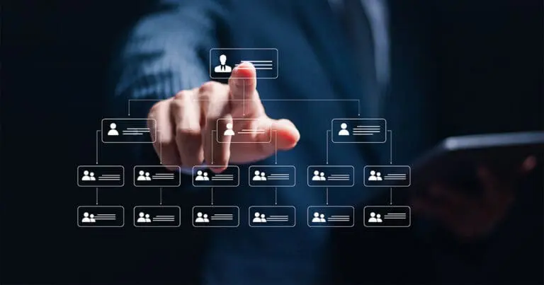 A person in a suit reaches forward to tap a glowing digital node in a hierarchical organizational chart made of connected user icons. The interface hovers over a dark background, suggesting a tech-driven approach to managing or restructuring teams.