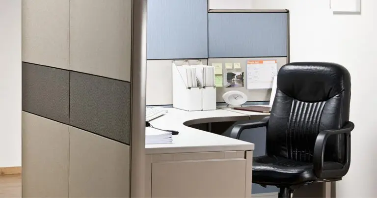 Empty office cubicle with a black desk chair pulled up to a workstation, surrounded by folders, notes, and office supplies. The unoccupied workspace conveys a sense of staffing gaps or employee turnover, aligning with the challenges technical debt can create for workforce productivity and retention.
