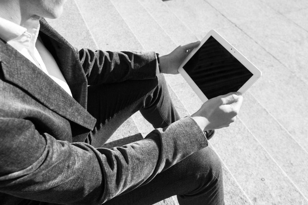 person sitting on steps using a tablet