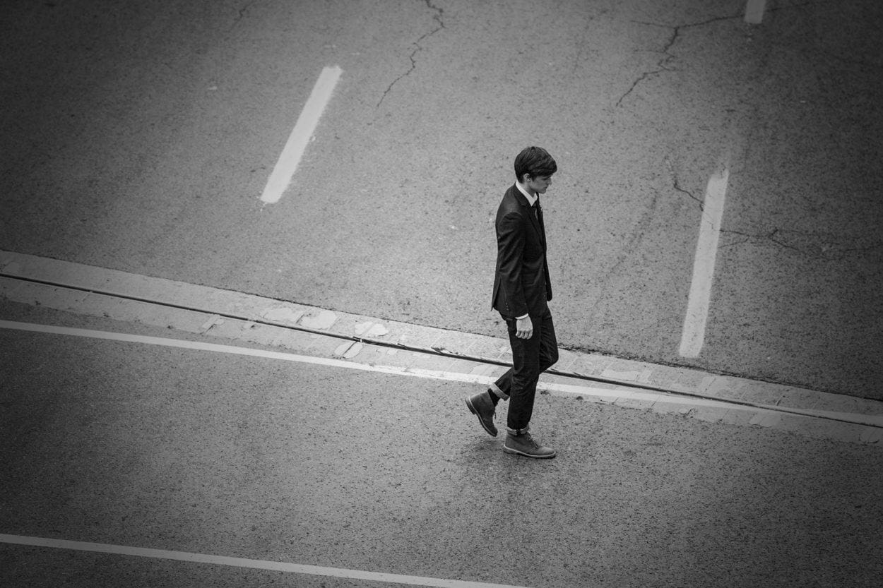 top view of a person walking on a street dressed in a suite jacket and jeans