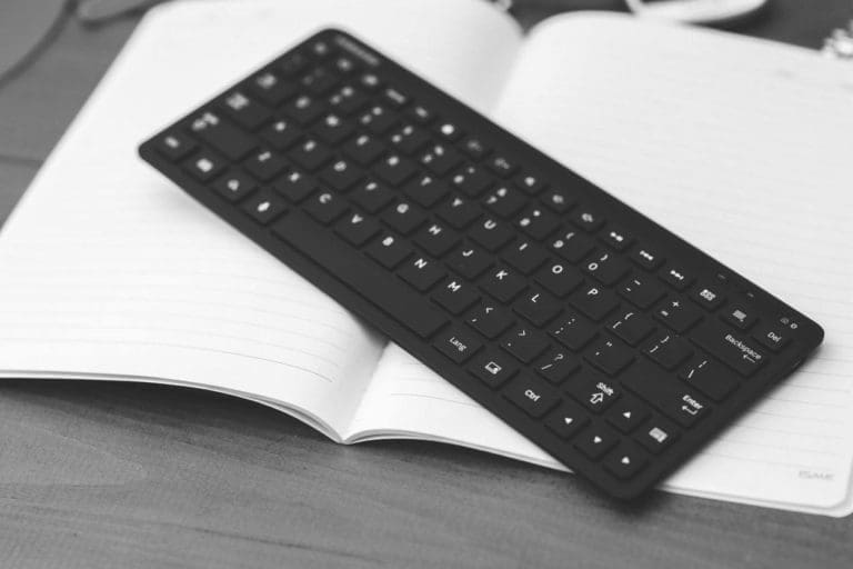compact computer keyboard laying on top of an open notebook