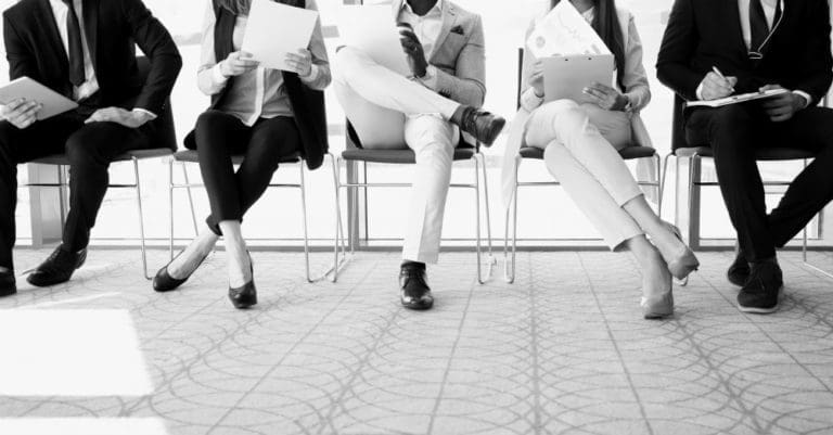 several applicants holding their resumes sitting next to each other