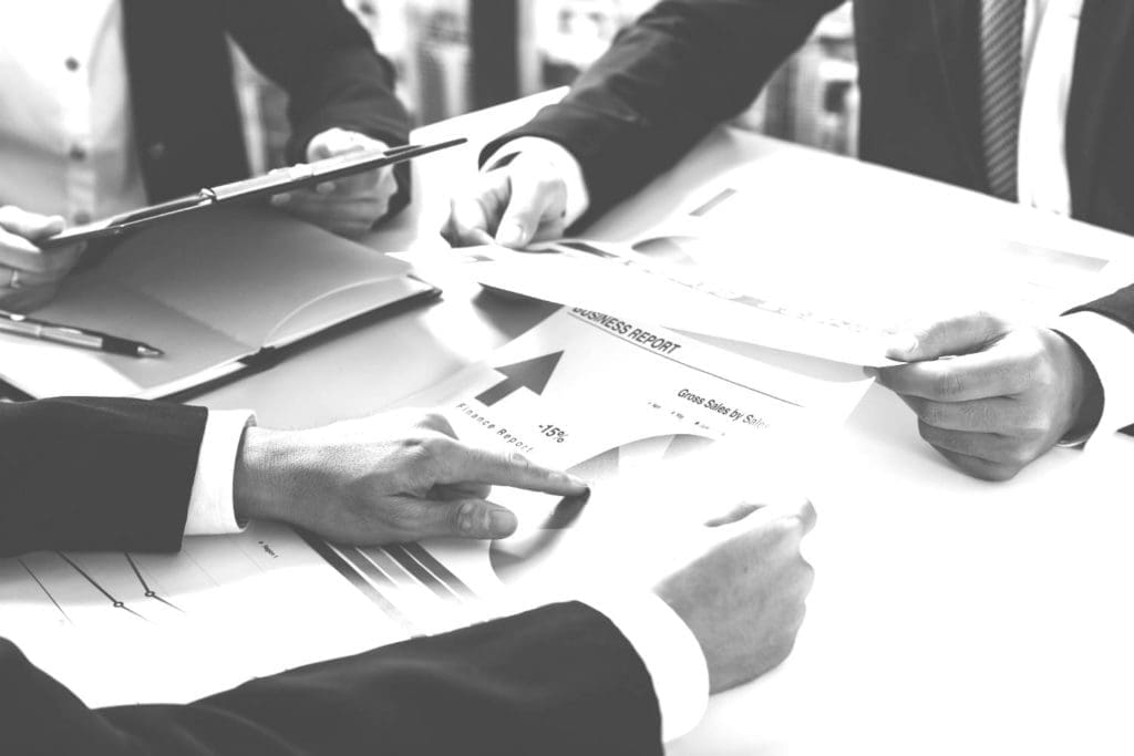 Three people working behind a desk with printed graphs scattered around