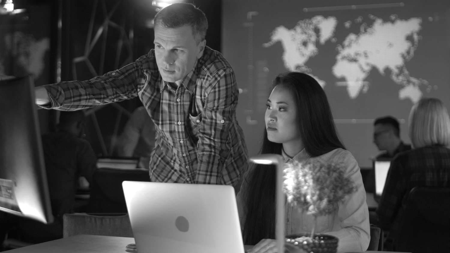 wo computer professionals collaborating while looking at a laptop screen